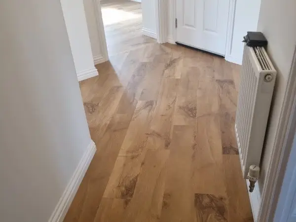 A hallway featuring newly installed Karndean Van Gogh Auckland Oak flooring. The oak planks exhibit a rich, warm brown color with natural wood grain patterns that add texture and depth to the space.